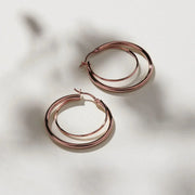 Rose gold Najo whirlpool hoops displayed elegantly on a white background, highlighting their unique design and shine.